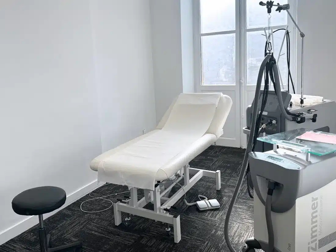 Salle de soin du centre My Laser Bordeaux : table de traitement, laser d'épilation et système de refroidissement devant une grande fenêtre