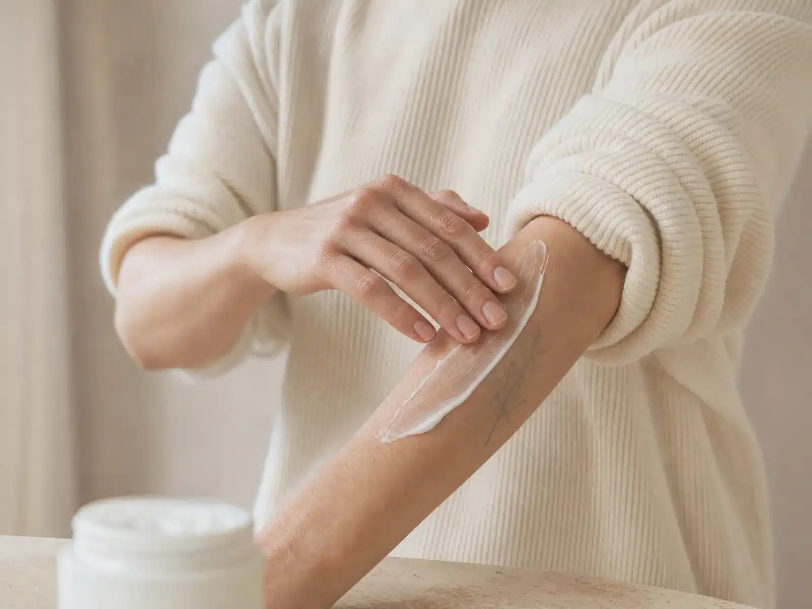 Soin après un détatouage laser à Toulouse : crème apaisante appliquée du bout des doigts sur un tatouage estompé de l'avant-bras