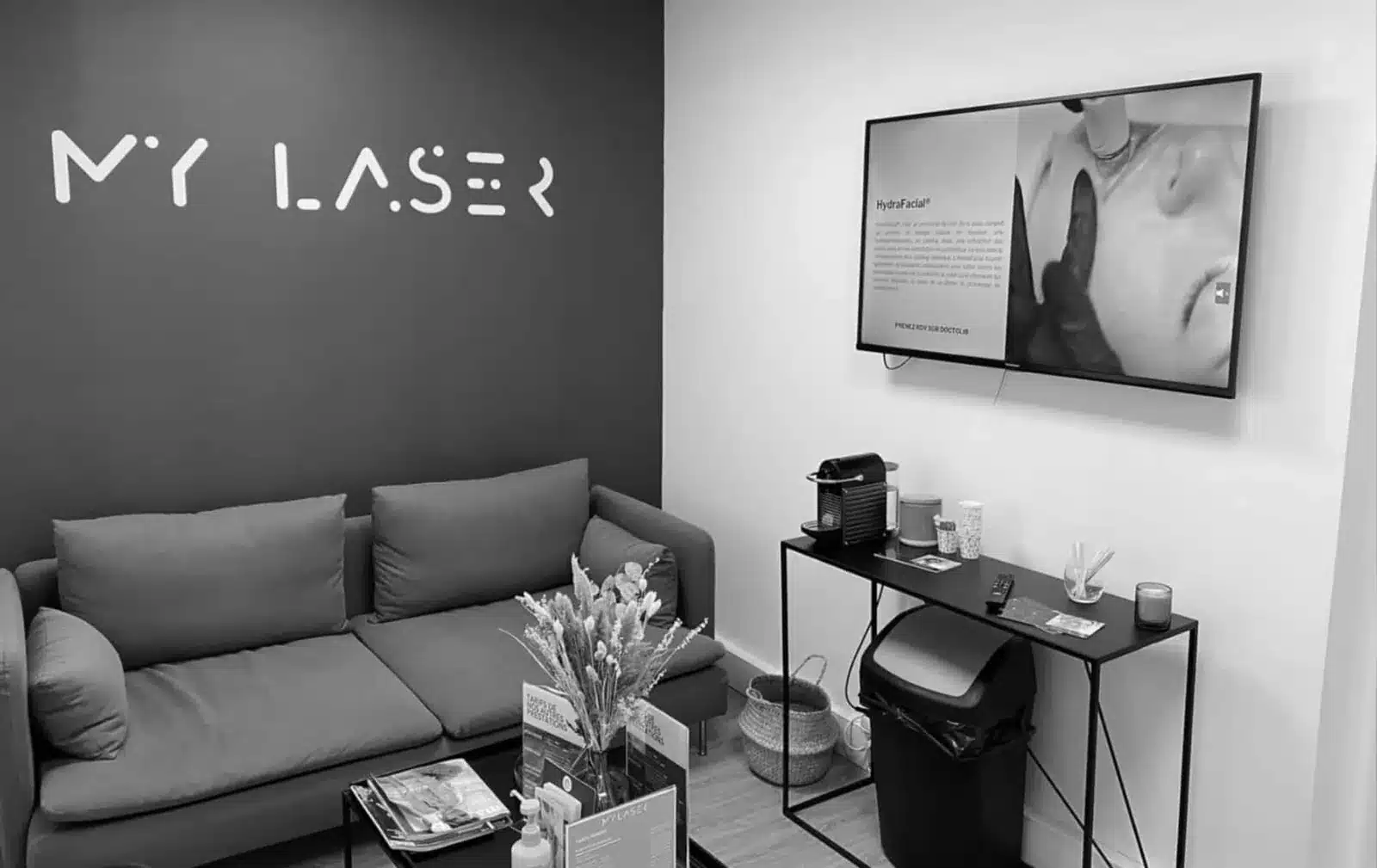 Salle d’attente d’un centre My Laser, logo au mur et canapé