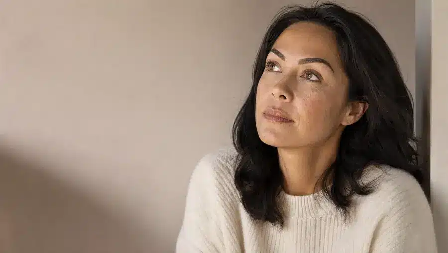 Gros plan d'une femme à la peau beige chaud aux sourcils semi-permanents foncés et trop marqués, yeux ouverts levés vers le haut