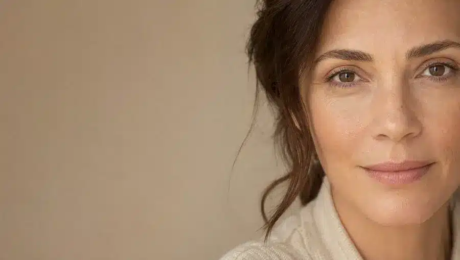 Gros plan sur le regard d'une femme d'une quarantaine d'années à la peau beige chaud, dessous des yeux lisse et reposé, yeux tournés vers l'objectif