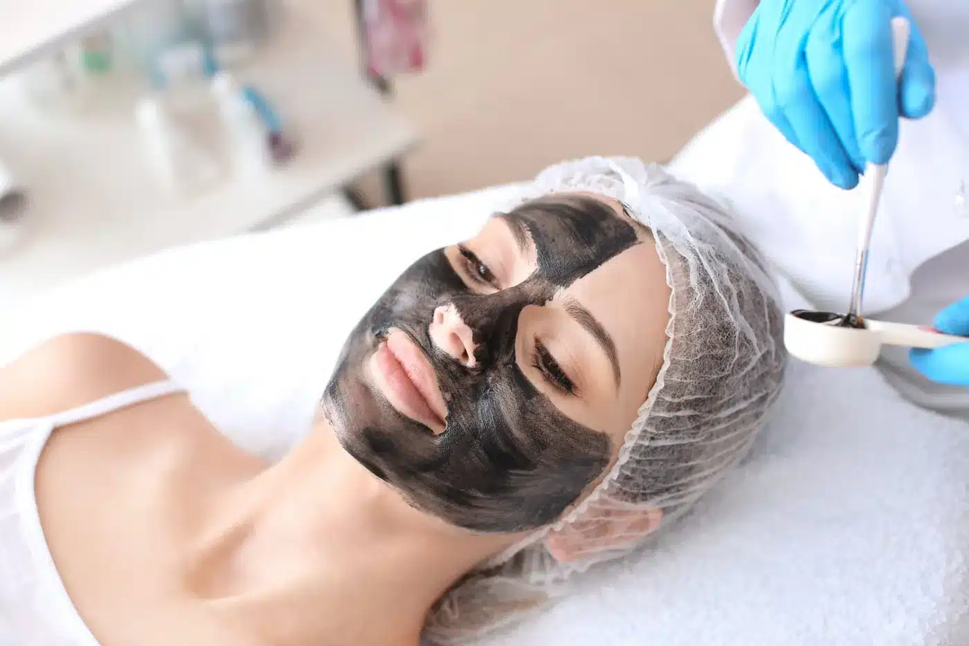 Application d'un masque au carbone sur le visage d'une patiente