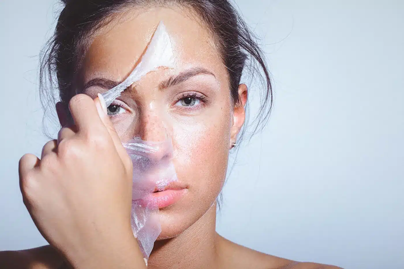 Femme retirant un film de soin transparent de son visage