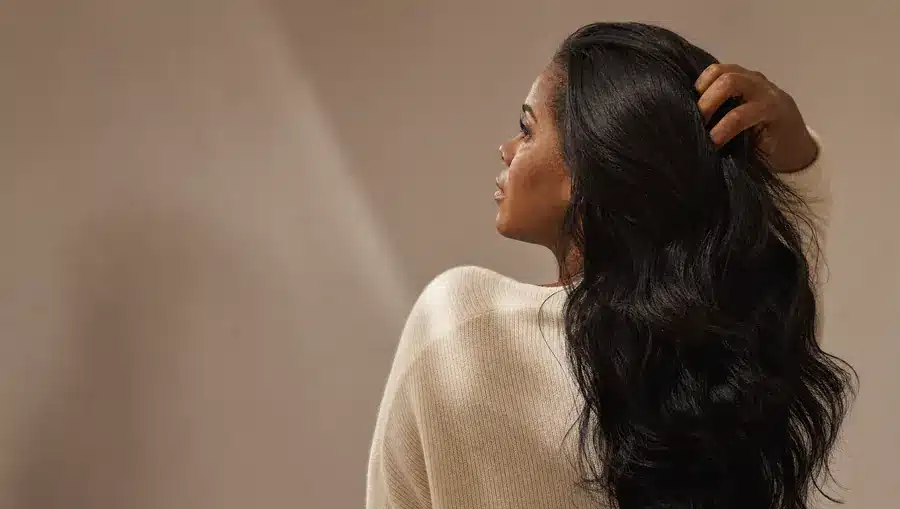 Femme passant la main dans une chevelure brune épaisse et brillante