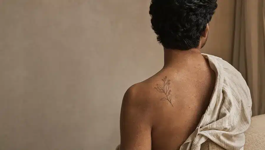 Dos d'un homme portant un tatouage botanique fin sur l'omoplate